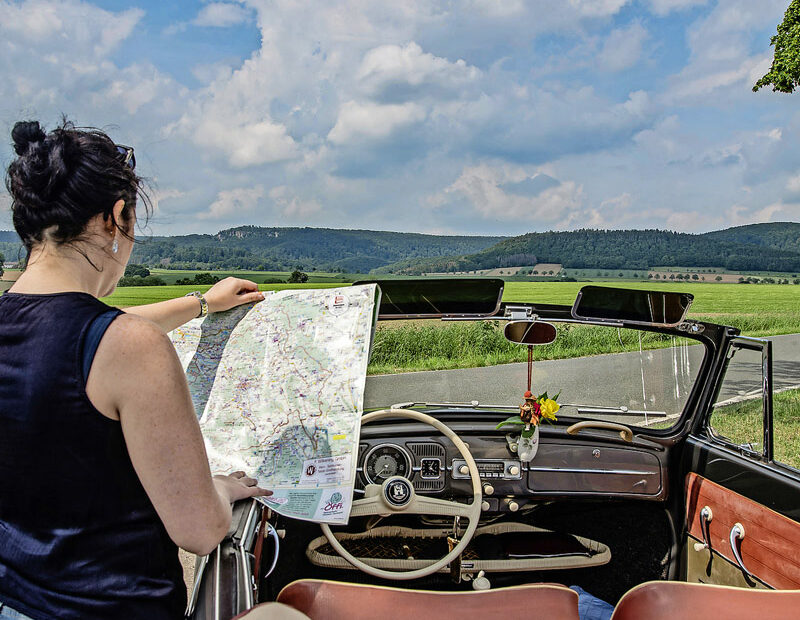 Frau im Cabrio liest Landkarte, Blick aufs Weserbergland